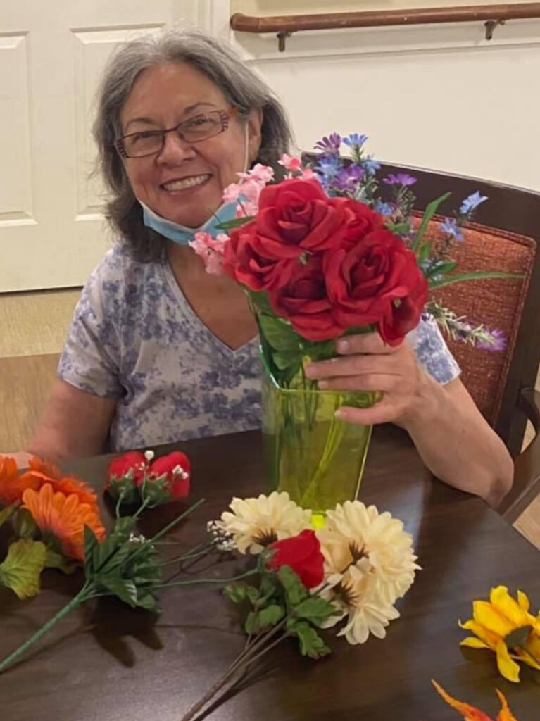 A caring volunteer arranging vases with beautiful flowers for a memory care resident.
