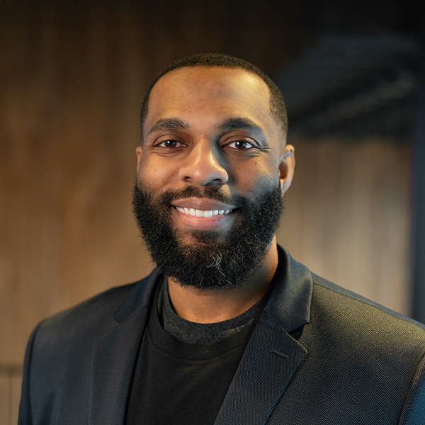Kevin Banks, Executive Director at Carriage Court Senior Living, smiling in a black blazer against a softly lit wooden background.