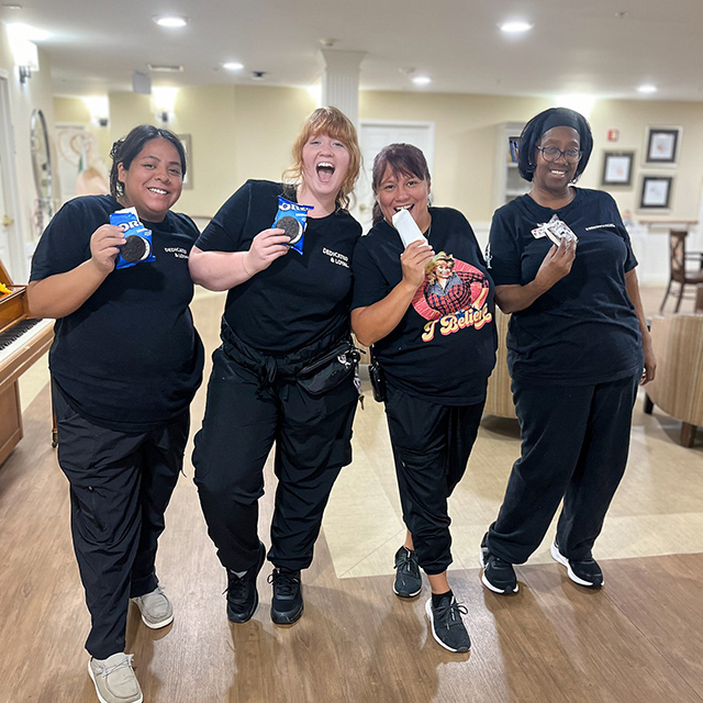 Four team members at Carriage Court Senior Living smile and pose playfully while enjoying ice cream.