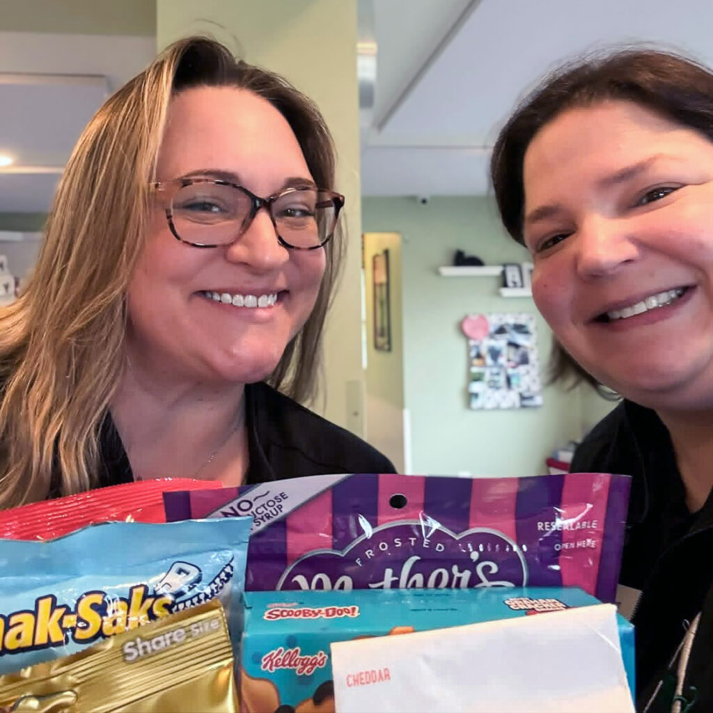 Two women smile with a gift basket for Small Business Day.