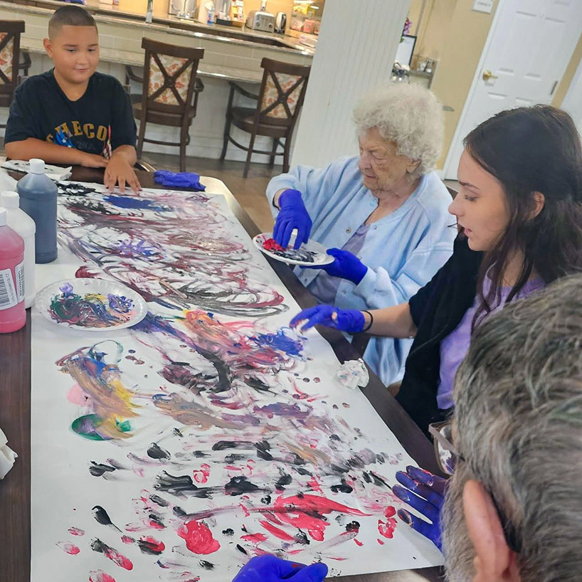 Loved ones and seniors create a large piece of abstract art at Carriage Court Senior Living.