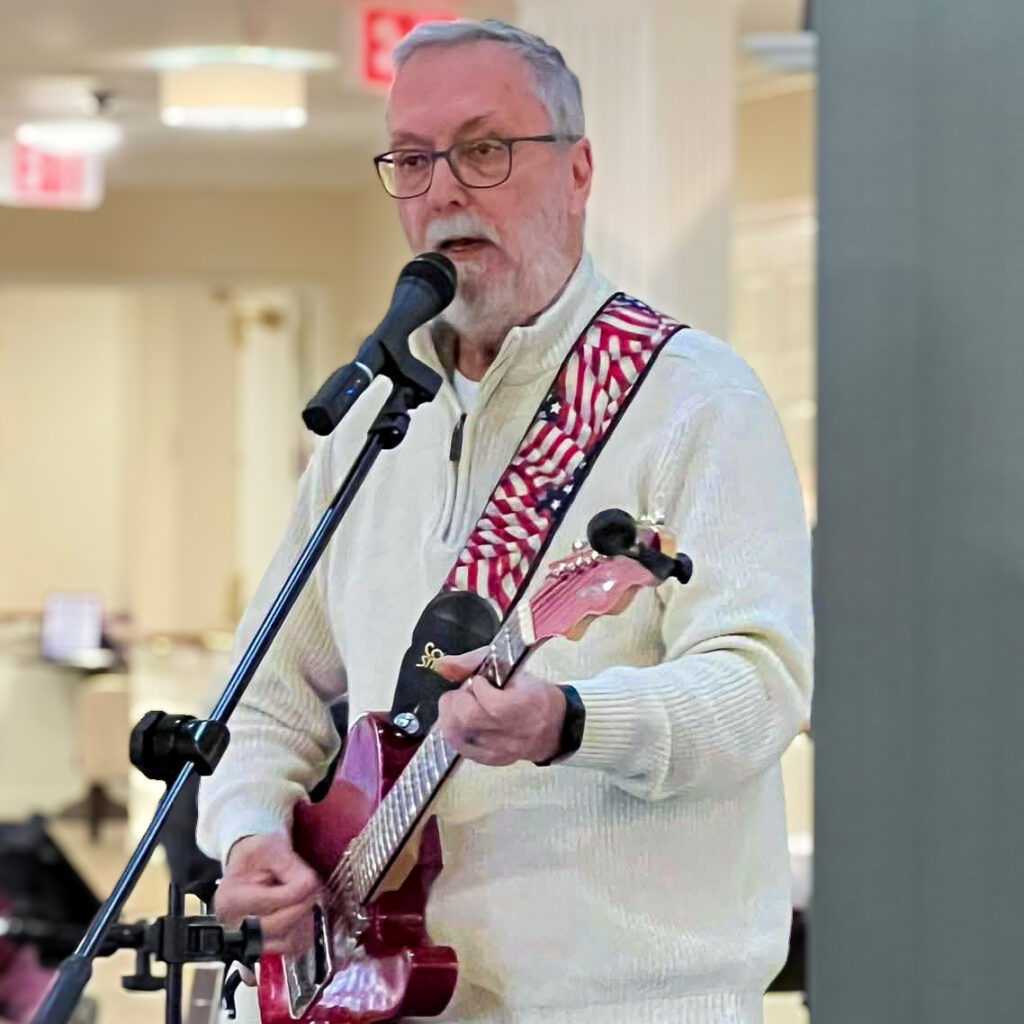 A man sings and plays the guitar during a performance at Carriage Court.